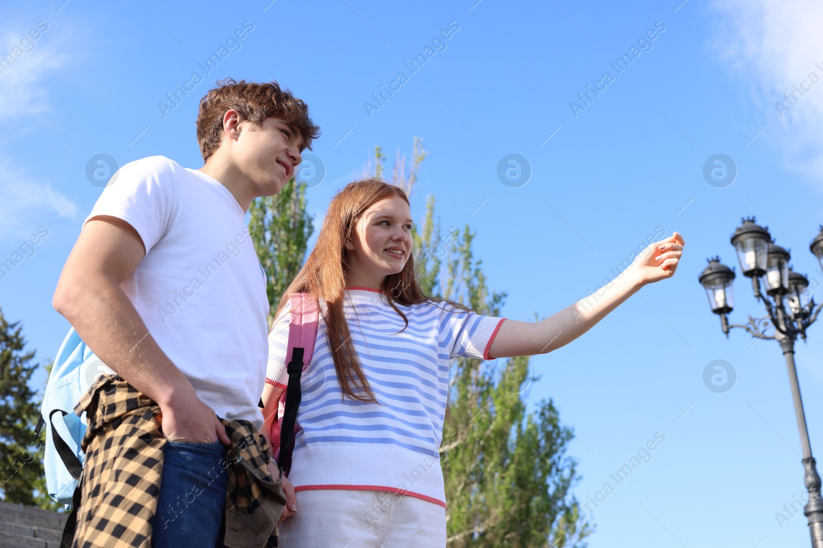 Teenage girl and boy walking together outdoors, low angle view Photo of Teenage girl and boy walking together outdoors, low angle view