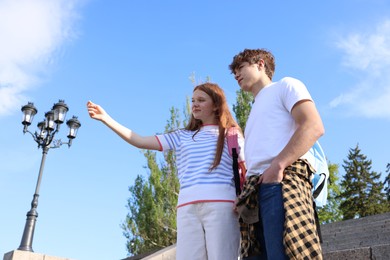 Photo of Teenage girl and boy walking together outdoors, low angle view