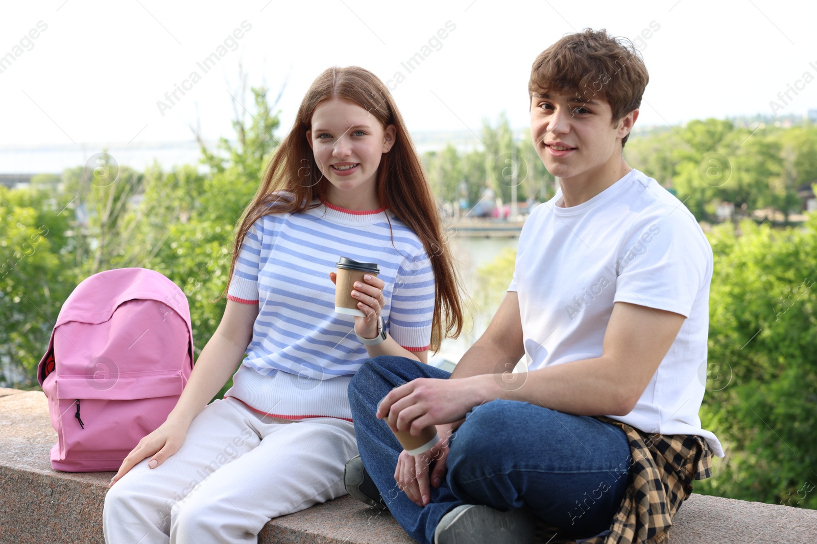 Teenage girl and boy with drinks outdoors Photo of Teenage girl and boy with drinks outdoors