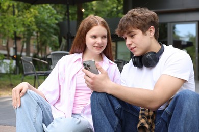 Photo of Teenage girl and boy with smartphone outdoors