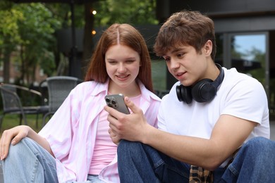Photo of Teenage girl and boy with smartphone outdoors