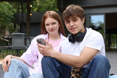 Photo of Teenage girl and boy with smartphone outdoors