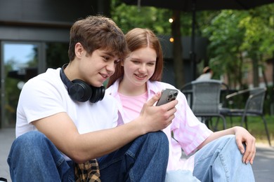 Photo of Teenage girl and boy with smartphone outdoors