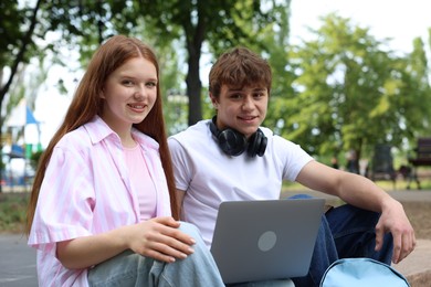 Photo of Teenage girl and boy with laptop outdoors