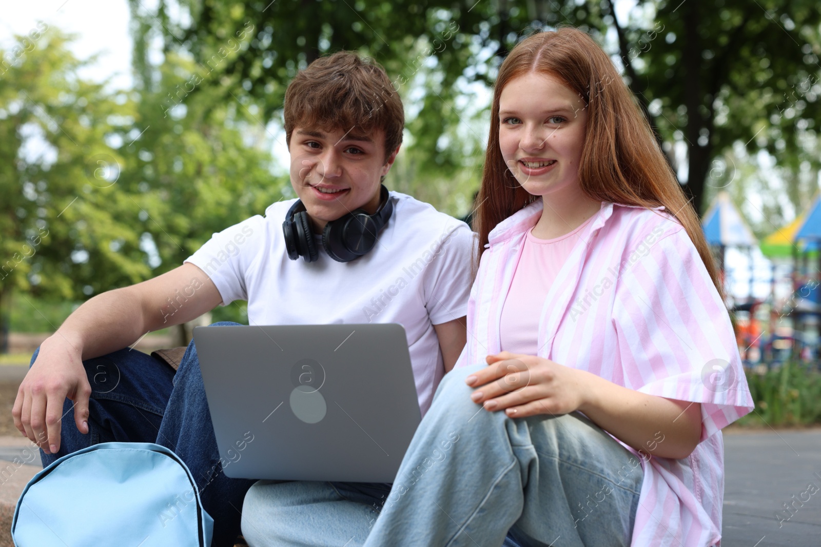 Teenage girl and boy with laptop outdoors Photo of Teenage girl and boy with laptop outdoors
