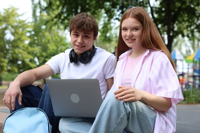 Photo of Teenage girl and boy with laptop outdoors