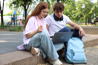 Photo of Teenage girl and boy with laptop outdoors