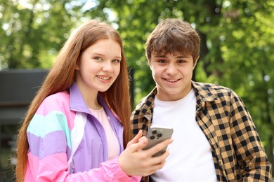 Photo of Teenage girl and boy with smartphone in park