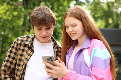 Photo of Teenage girl and boy with smartphone in park
