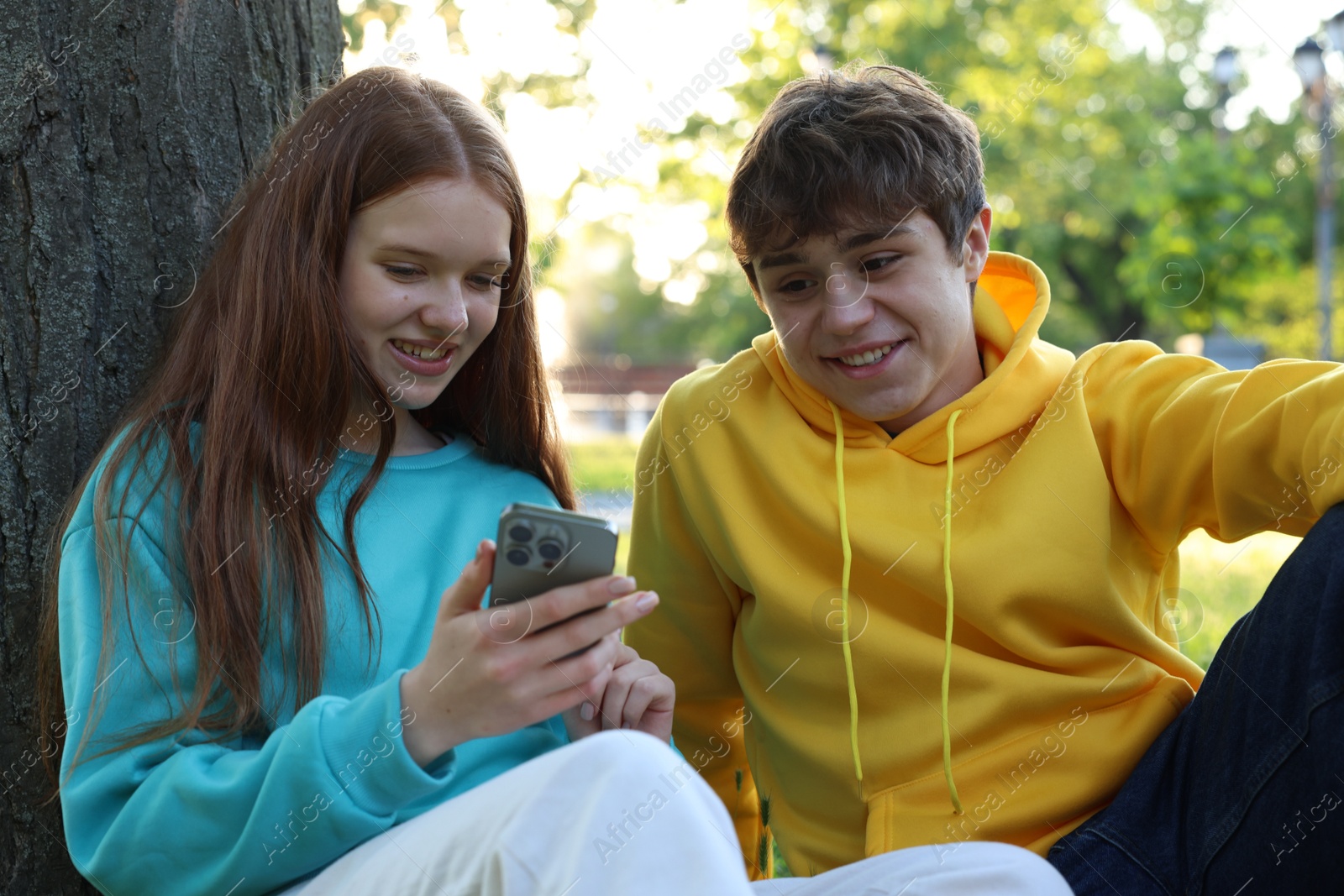 Photo of Teenage girl and boy with smartphone in park