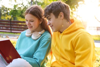 Photo of Teenage girl and boy reading together in park