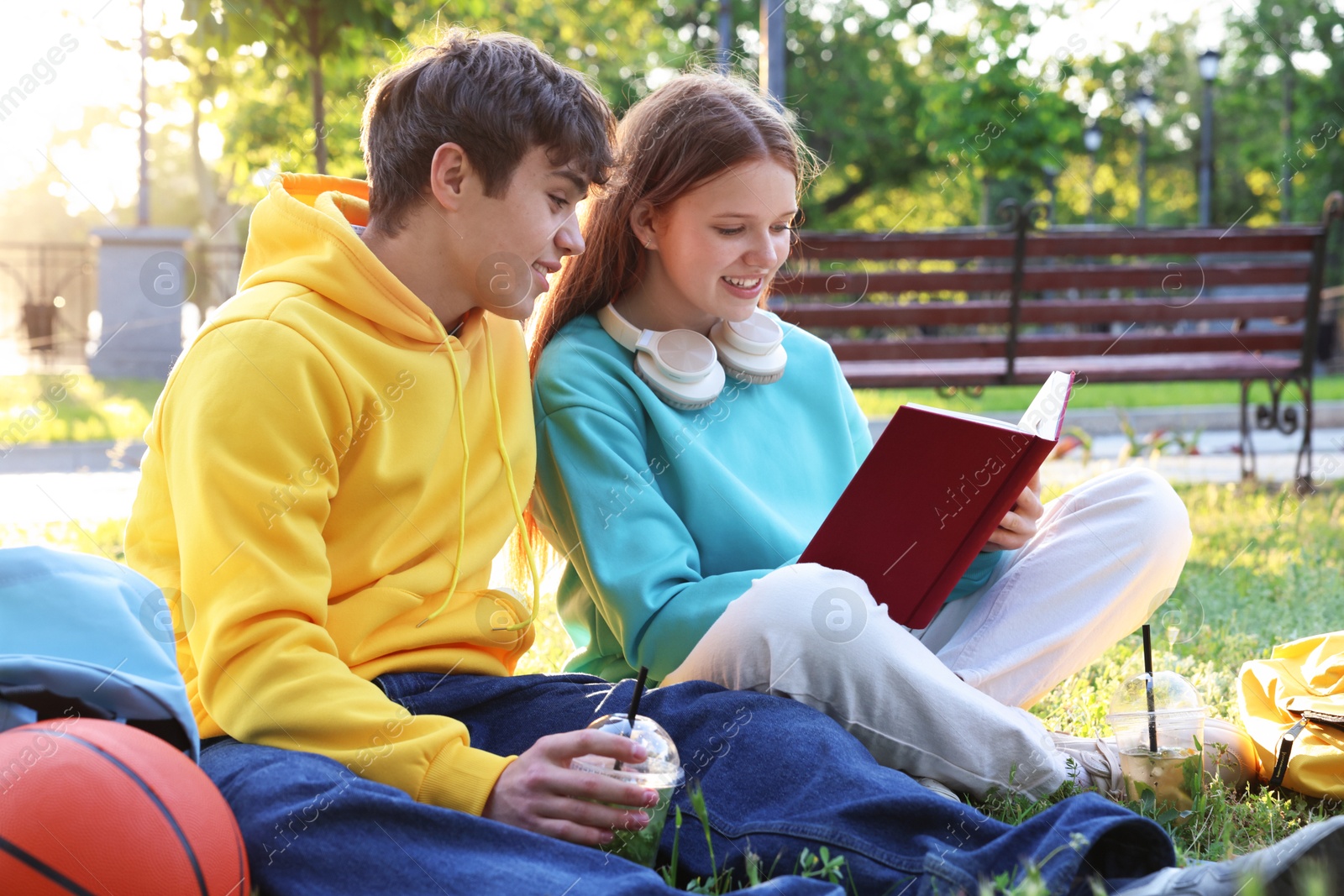 Teenage girl and boy reading together in park Photo of Teenage girl and boy reading together in park