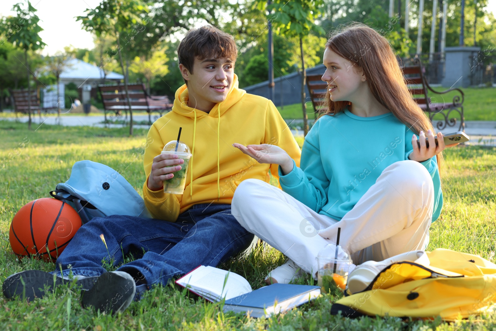 Teenage girl and boy with phone and books in park Photo of Teenage girl and boy with phone and books in park