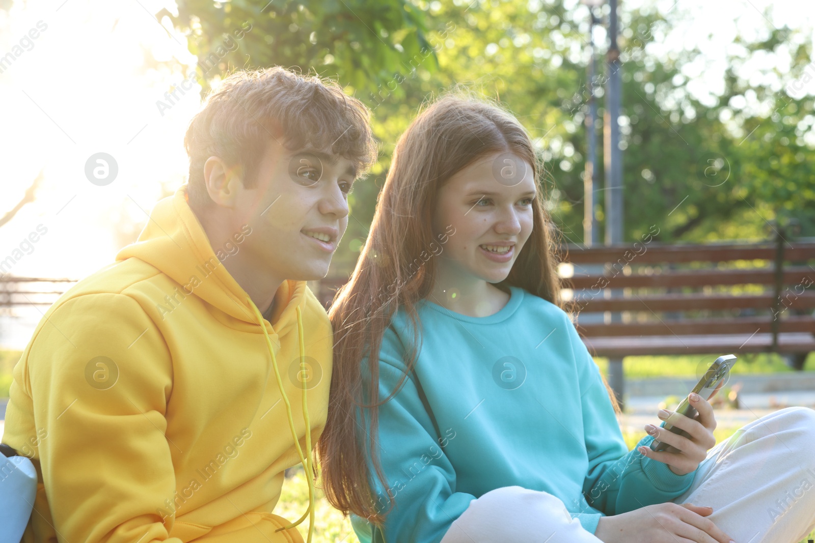 Teenage girl and boy with smartphone in park Photo of Teenage girl and boy with smartphone in park