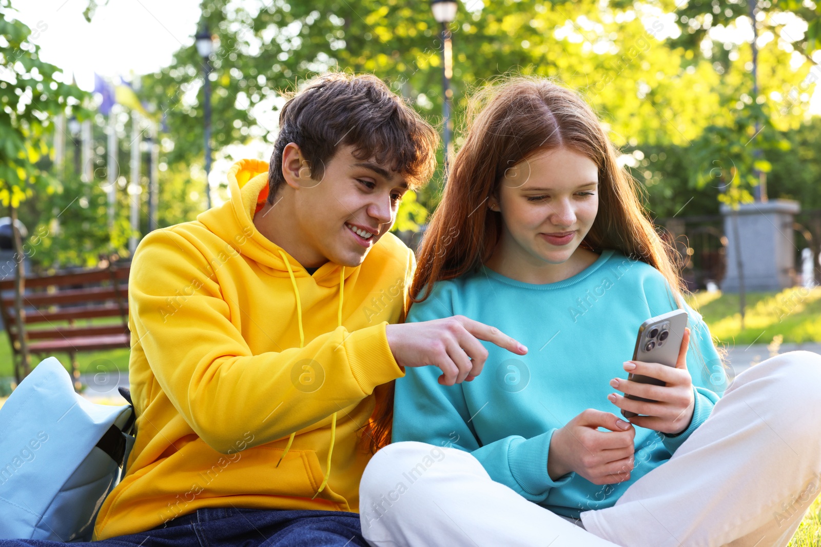Teenage girl and boy with smartphone in park Photo of Teenage girl and boy with smartphone in park