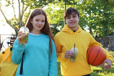 Photo of Teenage girl and boy with drinks and basketball in park
