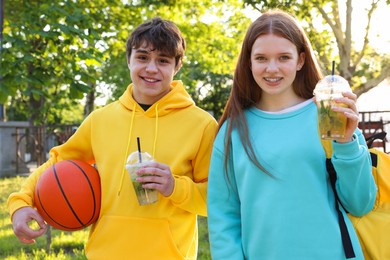 Photo of Teenage girl and boy with drinks and basketball in park