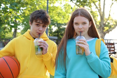 Photo of Teenage girl and boy with drinks and basketball in park