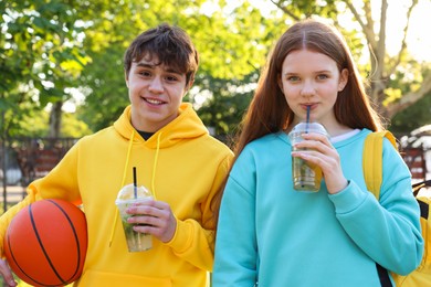 Photo of Teenage girl and boy with drinks and basketball in park