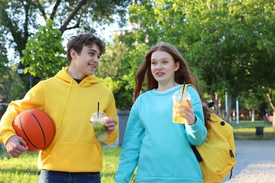Photo of Teenage girl and boy with drinks and basketball in park