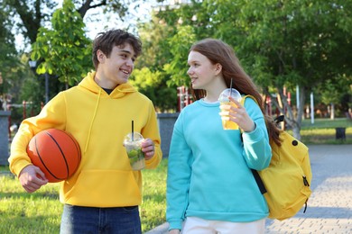 Photo of Teenage girl and boy with drinks and basketball in park