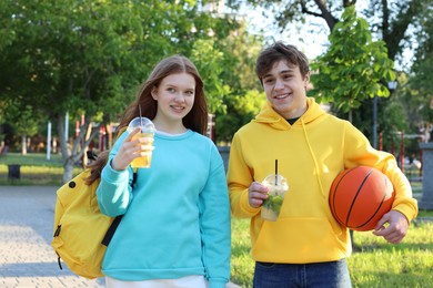 Photo of Teenage girl and boy with drinks and basketball in park