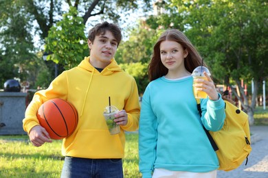Photo of Teenage girl and boy with drinks and basketball in park
