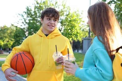 Photo of Teenage girl and boy with drinks and basketball in park