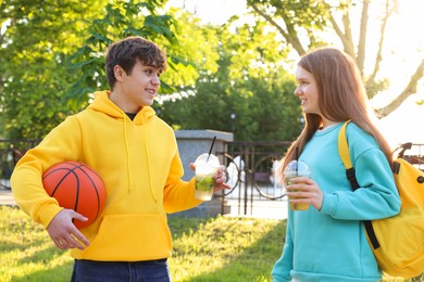 Photo of Teenage girl and boy with drinks and basketball in park