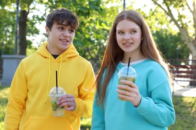 Photo of Teenage girl and boy with drinks in park