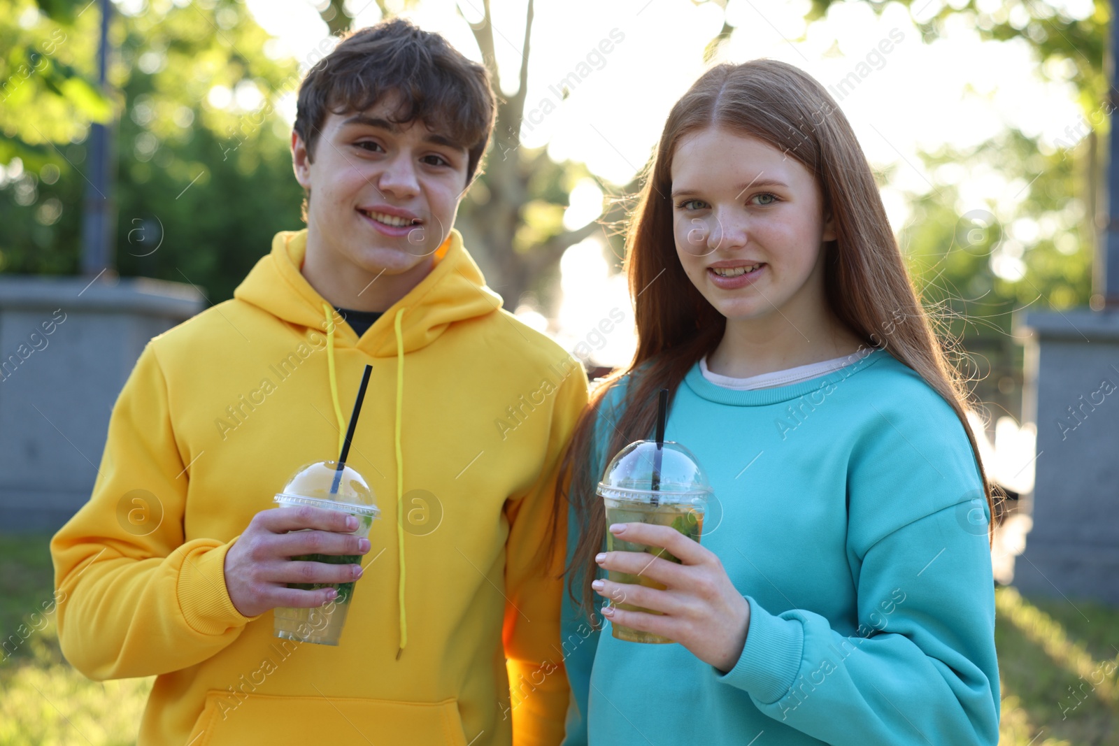 Photo of Teenage girl and boy with drinks in park