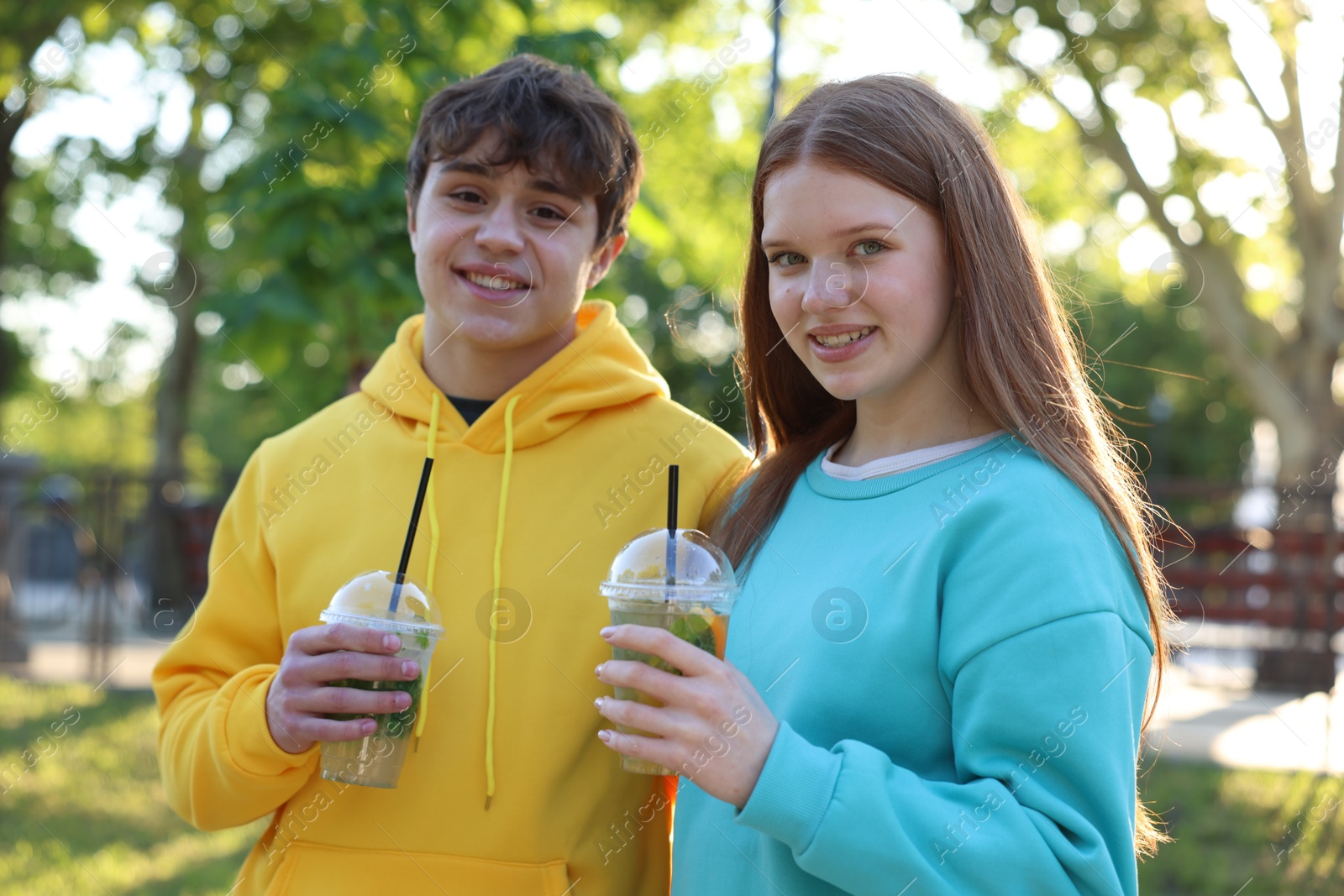 Teenage girl and boy with drinks in park Photo of Teenage girl and boy with drinks in park