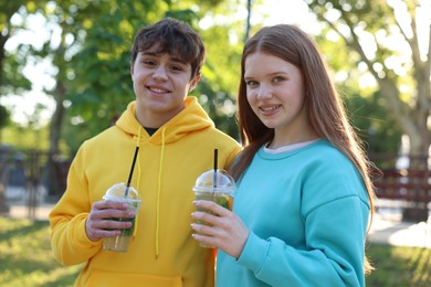 Photo of Teenage girl and boy with drinks in park