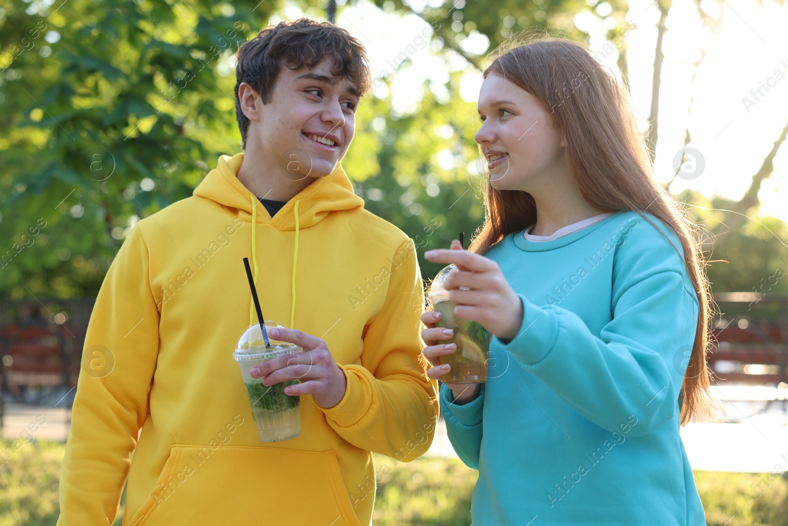 Teenage girl and boy with drinks in park Photo of Teenage girl and boy with drinks in park