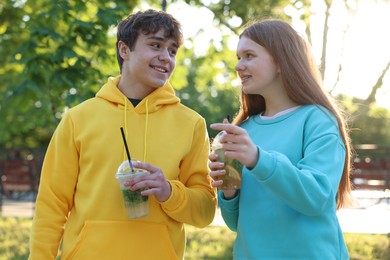 Photo of Teenage girl and boy with drinks in park