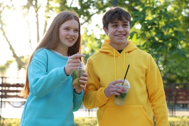 Photo of Teenage girl and boy with drinks in park