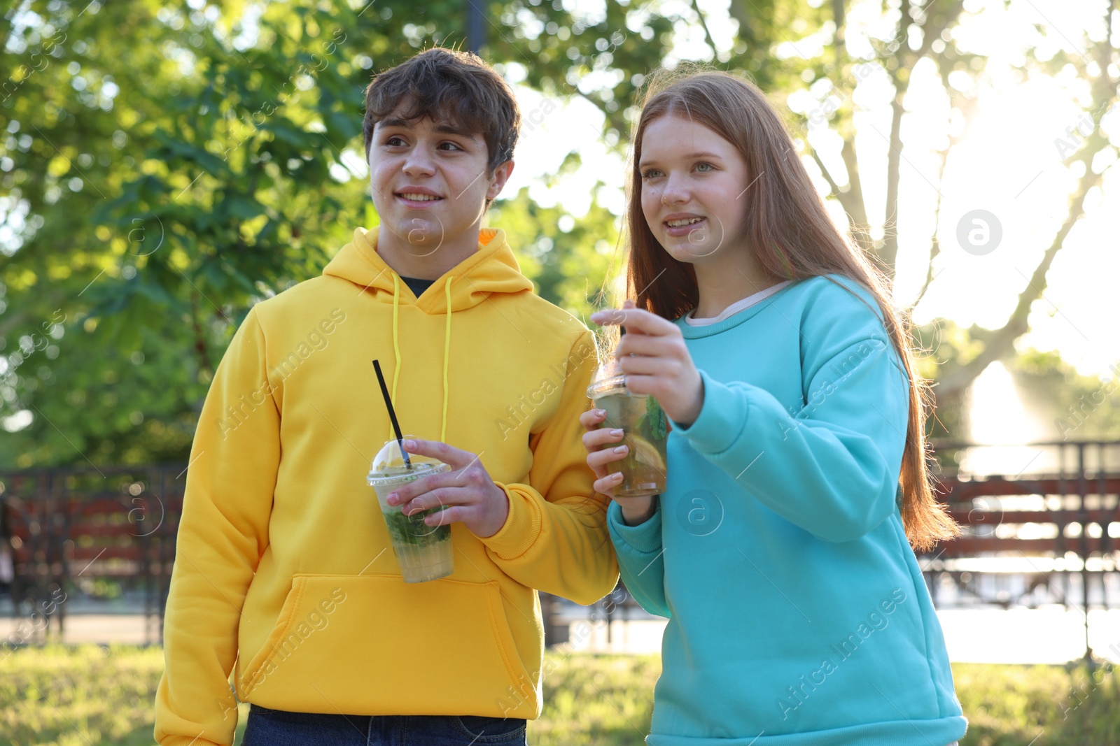 Teenage girl and boy with drinks in park Photo of Teenage girl and boy with drinks in park
