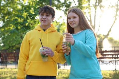Photo of Teenage girl and boy with drinks in park
