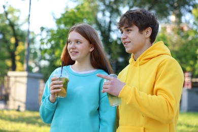 Photo of Teenage girl and boy with drinks in park