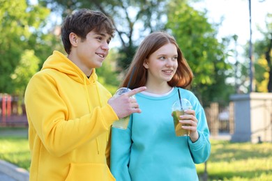 Photo of Teenage girl and boy with drinks in park