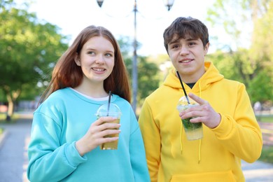Photo of Teenage girl and boy with drinks in park