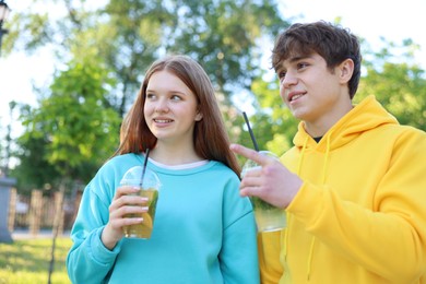 Photo of Teenage girl and boy with drinks in park