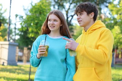 Photo of Teenage girl and boy with drinks in park