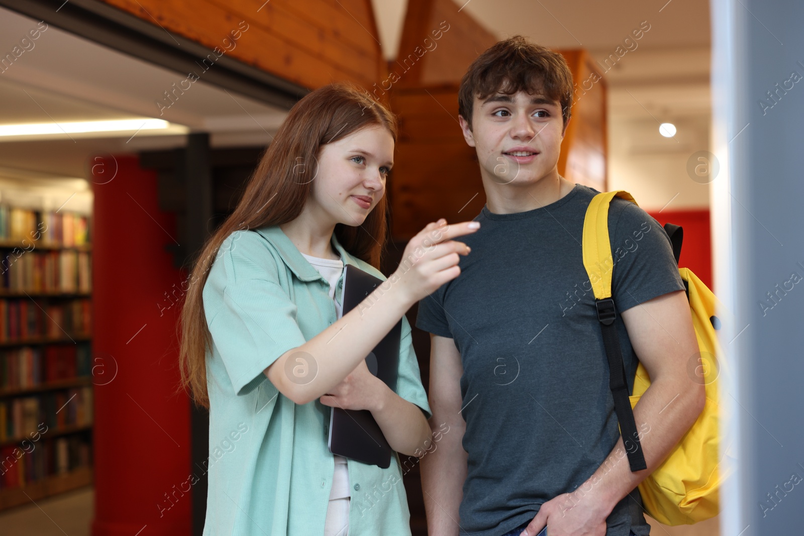 Teenage girl and boy with laptop in book store Photo of Teenage girl and boy with laptop in book store