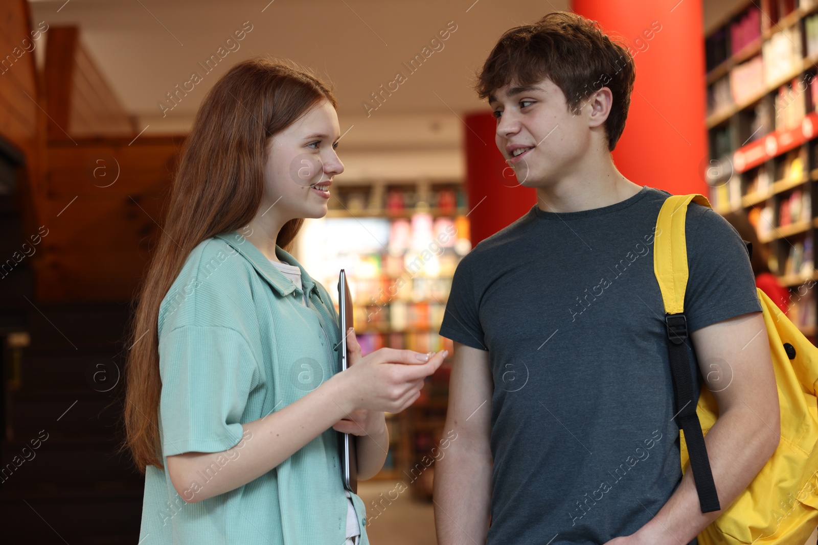 Teenage girl and boy with laptop in book store Photo of Teenage girl and boy with laptop in book store