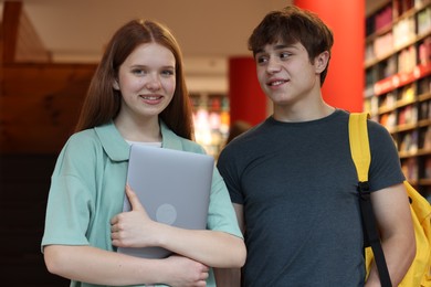 Photo of Teenage girl and boy with laptop in book store