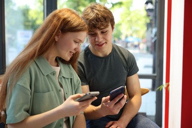 Photo of Teenage girl and boy with phones indoors