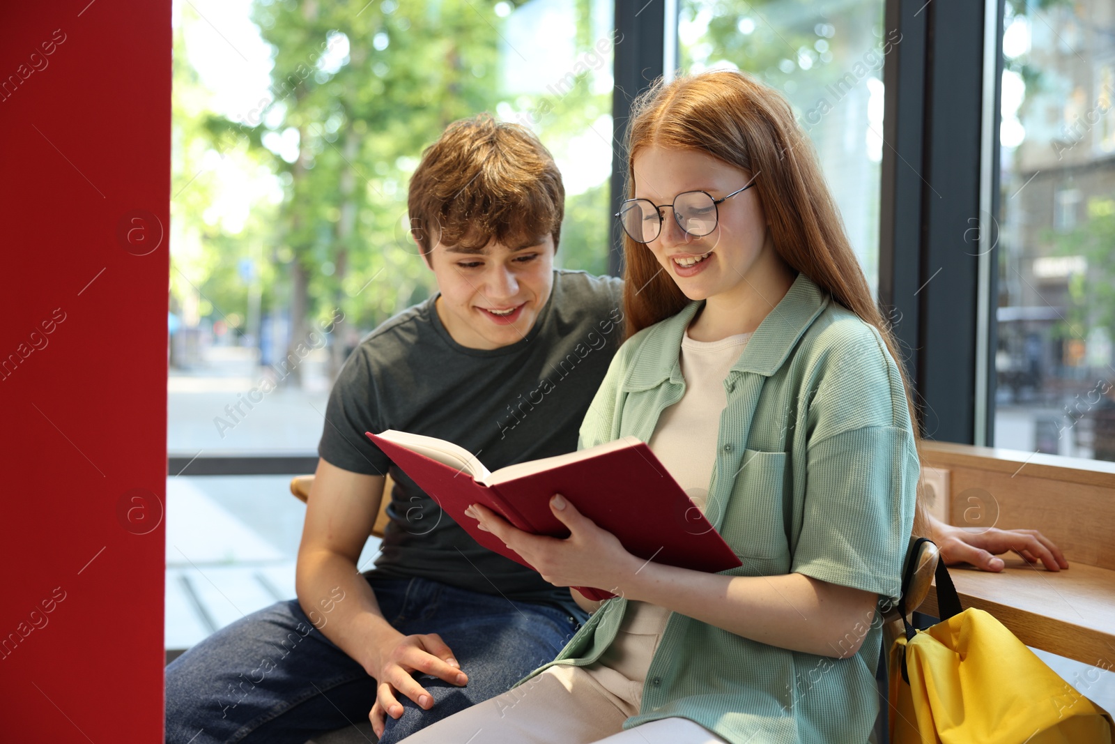 Teenage girl and boy reading book indoors Photo of Teenage girl and boy reading book indoors