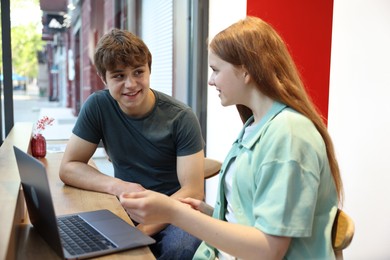 Photo of Teenage girl and boy with laptop indoors