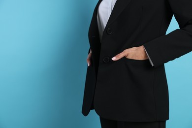 Photo of Confident business woman in suit on light blue background, closeup. Space for text